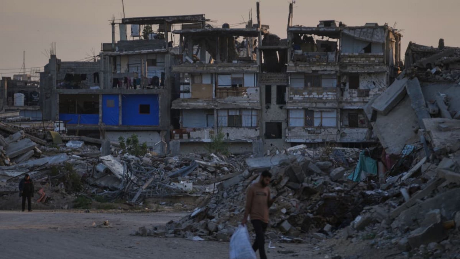 Palästinenser gehen im südlichen Gazastreifen eine Straße entlang, die von Gebäuden umgeben ist, die bei israelischen Luft- und Bodenoperationen zerstört wurden. (Archivbild).Abdel Kareem Hana/AP/dpa Palästinenser gehen im südlichen Gazastreifen eine Straße entlang, die von Gebäuden umgeben ist, die bei israelischen Luft- und Bodenoperationen zerstört wurden. (Archivbild).Abdel Kareem Hana/AP/dpa