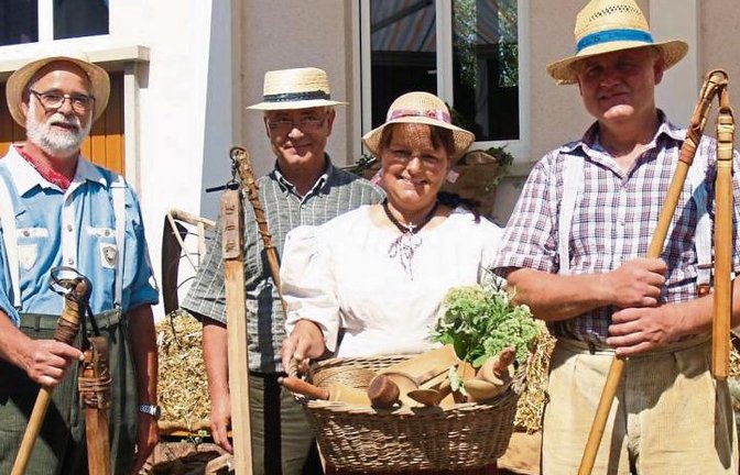 Kleidung und Arbeitsgeräte verraten die bäuerliche Herkunft. Für die alte Tradition der Sichelhengetse begeistern sich auch die „drei Drescher vom Dienst“ (von links): Martin Gaupp, Helmut Oehler und Manfred Pfeil. Ursula Pfeil zeigt einen Korb mit alten 