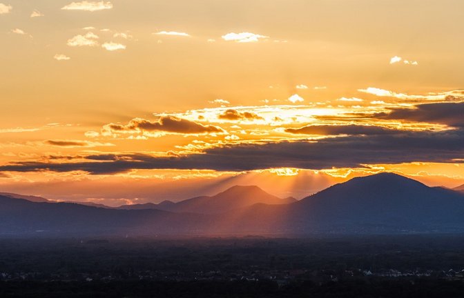 Der Tag neigt sich dem Ende: Farbenprächtig wirft die untergehende Sonne ihr Licht zwischen den Gipfeln der französischen Vogesen hindurch auf das Rheintal.<span class='image-autor'>Foto: Philipp von Ditfurth/dpa</span>