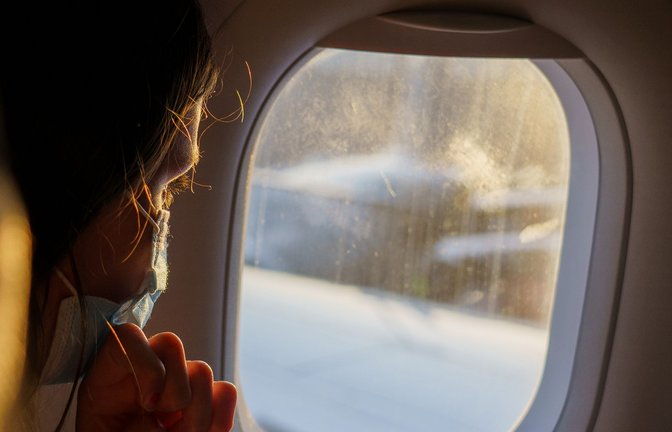 Ein  Fluggast mit Maske schaut vor dem Start aus dem Fenster. Die zuständigen EU-Behörden haben damit begonnen, ihre Corona-Maßnahmen für den Luftverkehr zu lockern.<span class='image-autor'>Foto: dpa/Andreas Arnold</span>