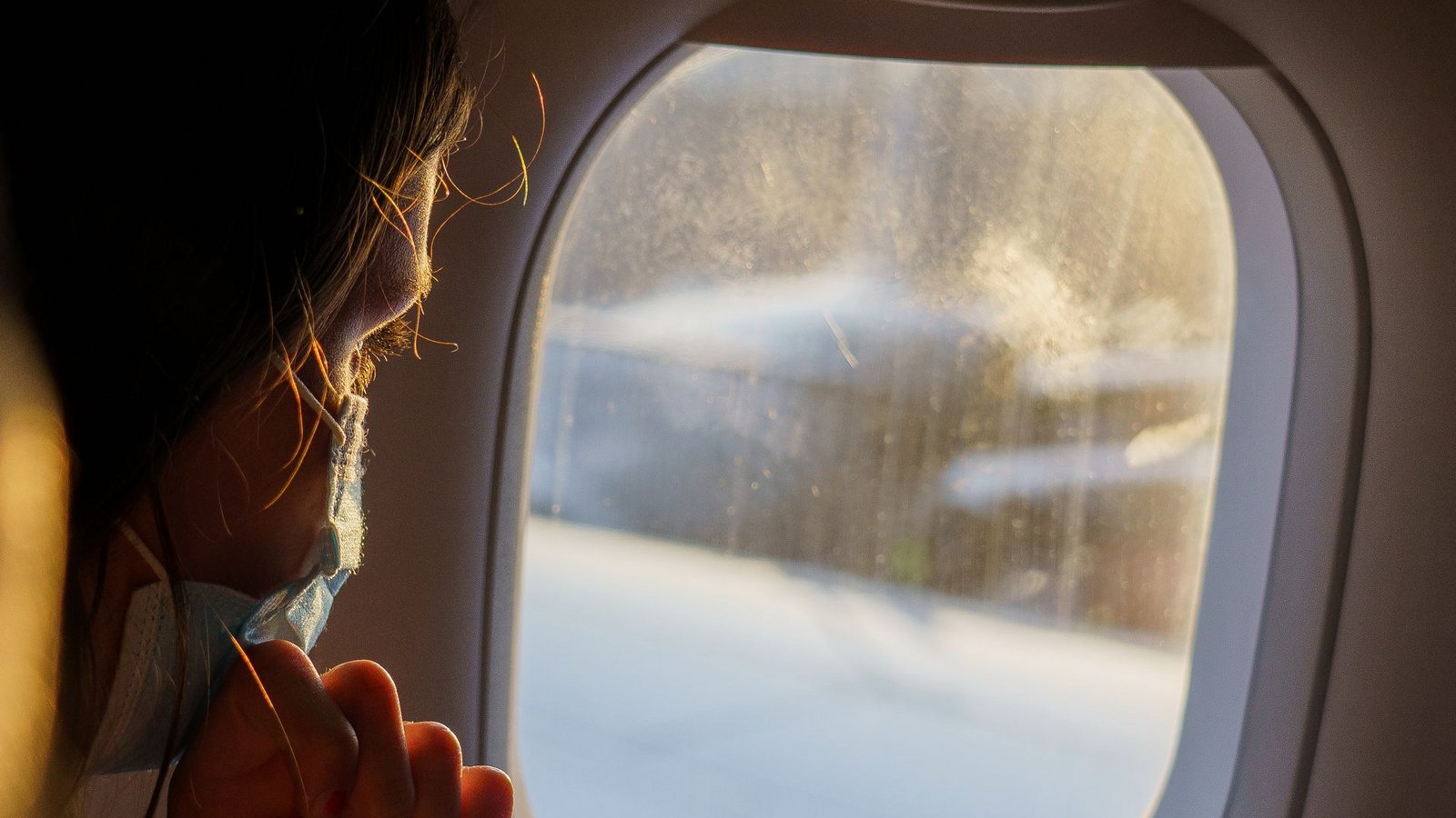 Ein  Fluggast mit Maske schaut vor dem Start aus dem Fenster. Die zuständigen EU-Behörden haben damit begonnen, ihre Corona-Maßnahmen für den Luftverkehr zu lockern.Foto: dpa/Andreas Arnold