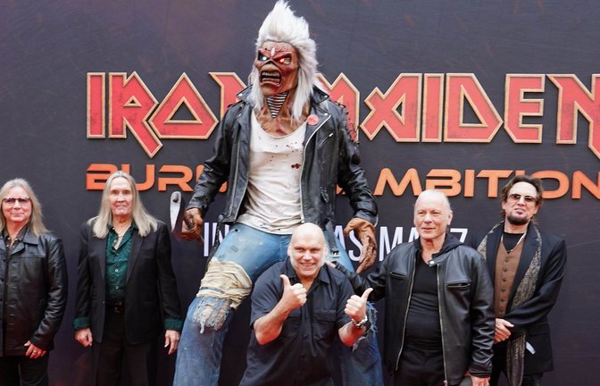 Die Bandmitglieder von Iron Maiden bei der Weltpremiere des Dokumentarfilms „Burining Ambition“ – Maskottchen Eddie darf natürlich nicht fehlen.<span class='image-autor'>Foto: Ian West/PA Wire/dpa/Ian West</span>