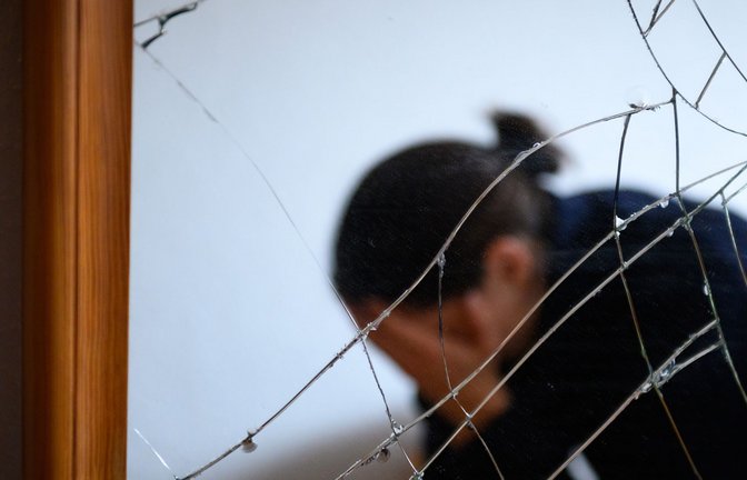 Eine Frau sitzt neben einem gesprungenen Spiegel auf einem Bett und hält ihren Kopf in den Händen. Ein Gesetzentwurf soll Frauen besser vor Gewalt schützen (Symbolfoto).<span class='image-autor'>Foto: Jonas Walzberg/dpa/Jonas Walzberg</span>