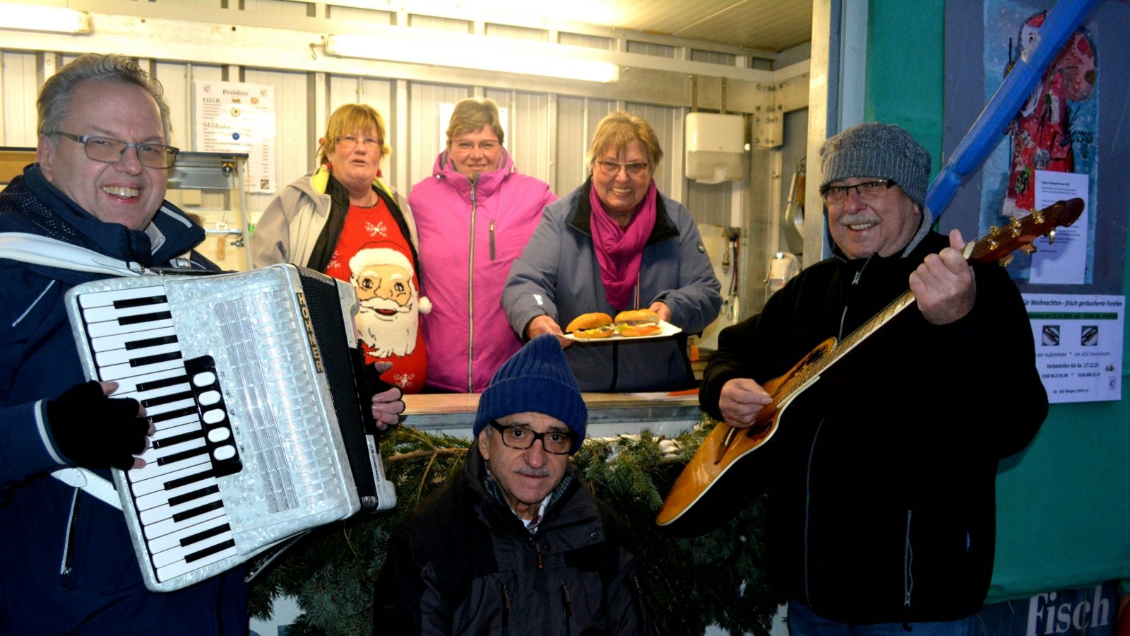 Mit musikalischen Weihnachtsgrüßen verabschiedeten sich die Mitglieder des Angelsportvereins (ASV) Illingen von ihren Gästen am Fischwagen auf dem Schillerplatz in die Winterpause. Am letzten Verkaufstag in diesem Jahr fehlte auch dieses Mal das Trio „Top 3“ nicht. Ottmar Kurbel, Heinz Sibert und Reimund Scheytt erfüllten den Platz mit Melodien bekannter Weihnachtslieder. „Herzlichen Dank an meine Fischwagenband“, freute sich die ASV-Vorsitzende Hedwig Ramstein, die kurzerhand den drei Musikern einen Namen passend zum Auftritt gab. Der ASV bietet schon traditionell über die Wintermonate auf dem Wochenmarkt Räucherfisch sowie Lachs- und Heringsbrötchen zum Verkauf an. Der Erlös fließe in die Vereinskasse, erklärte Ramstein. Unser Bild zeigt die „Fischwagenband“ mit Reimund Scheytt (v.l.), Ottmar Kurbel und Heinz Sibert und dem Fischwagenteam mit Sonja Mahler (v.l), Sabine Fechner und Hedwig Ramstein.  Foto: Stahlfeld