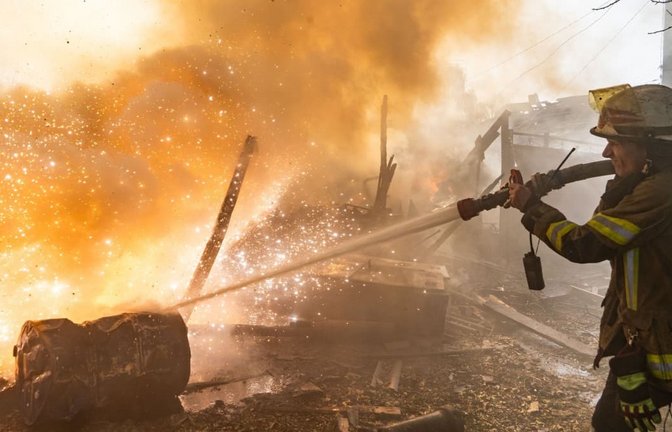 Eine Rettungskraft löscht einen Brand in Wohnhäusern, die bei einem russischen Angriff zerstört wurden.<span class='image-autor'>Andrii Marienko/AP/dpa</span>