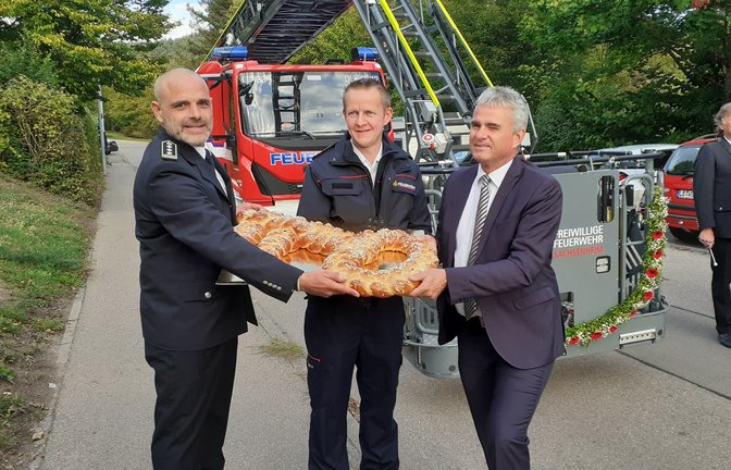 Stadtkommandant Philipp Rousta (l.) und Bürgermeister Holger Albrich (r.) übergeben Abteilungskommandant Armin Klein aus Kleinsachsenheim symbolisch einen Hefezopf-Schlüssel für den neuen Drehleiterwagen der Stadt Sachsenheim. <span class='image-autor'>Fotos: Glemser</span>