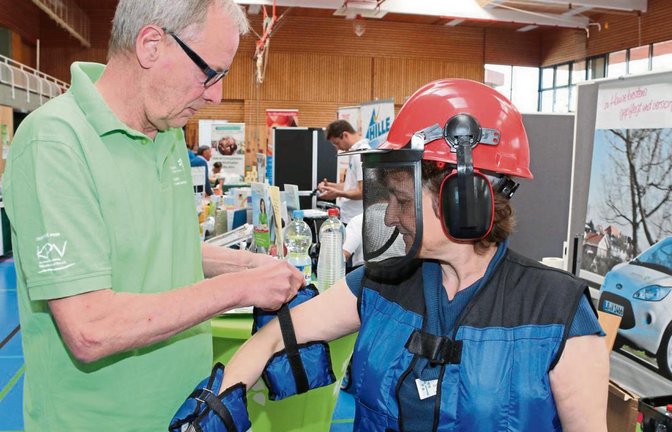 Reinhard Findeisen-Tietze, Betriebsleiter der Sozialstation, zieht zu Demonstrationszwecken Gabi Härle den Alterssimulationsanzug an.