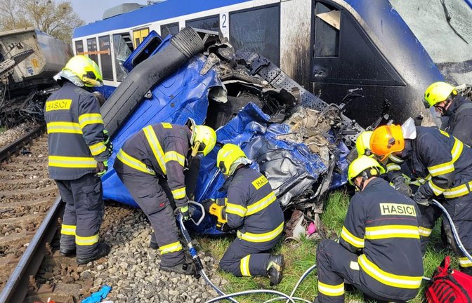 Feuerwehrleute arbeiten am Unglücksort, wo ein Personenzug und ein Lastwagen zusammengestoßen sind. Bei dem Unglück kam eine Person ums Leben, 21 Menschen wurden verletzt.<span class='image-autor'>Foto: -/Feuerwehr- und Rettungsdienst Trnava/TASR/dpa</span>
