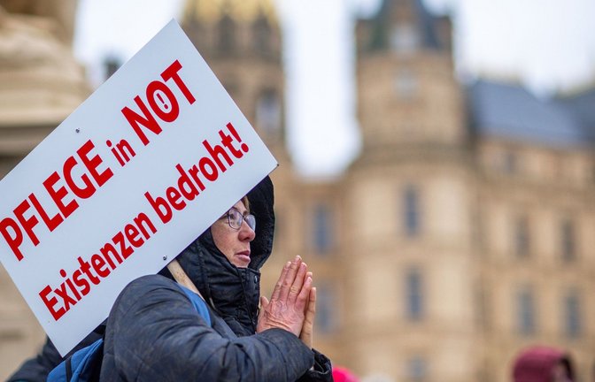 Bei einer Protestaktion vor dem Schweriner Landtag hält eine Teilnehmerin ein Schild mit der Aufschrift "Pflege in Not - Existenzen bedroht!".<span class='image-autor'>Foto: Jens Büttner/dpa</span>