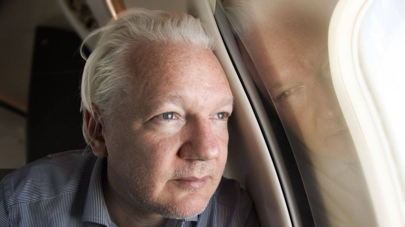 Julian Assange blickt aus dem Fenster des Flugzeuges, das auf dem Weg zum Gerichtsverfahren in Bangkok Zwischenhalt machen wird.Foto: IMAGO/AAP/IMAGO/SUPPLIED BY WIKILEAKS