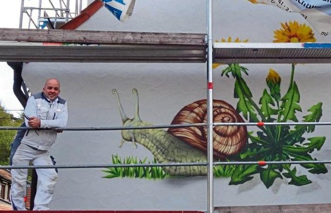 Vorab für die VKZ angehoben wurden die Planen über dem „Auricher Schneck“, der neuerdings ein Haus in der Hirsauer Straße in Aurich ziert. Sven Schmied von der Firma „Ihr Malermeister Tronser“ kann das Geheimnis um den Künstler lüften. Es sei der Bruder s