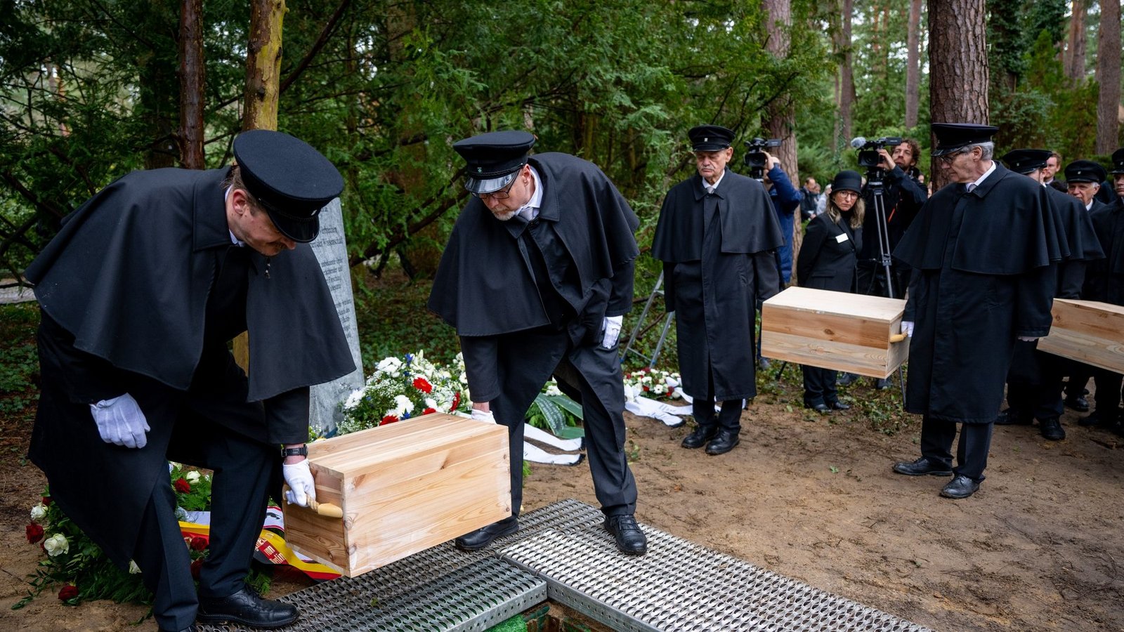 Die Gebeinekisten mit menschlichen Knochen werden nach der Trauerfeier in ein Grab auf dem Waldfriedhof Berlin-Dahlem hinabgelassen.Foto: Monika Skolimowska/dpa