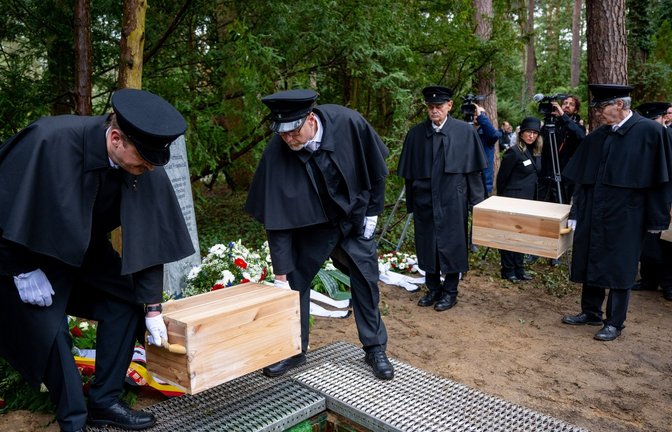 Die Gebeinekisten mit menschlichen Knochen werden nach der Trauerfeier in ein Grab auf dem Waldfriedhof Berlin-Dahlem hinabgelassen.<span class='image-autor'>Foto: Monika Skolimowska/dpa</span>