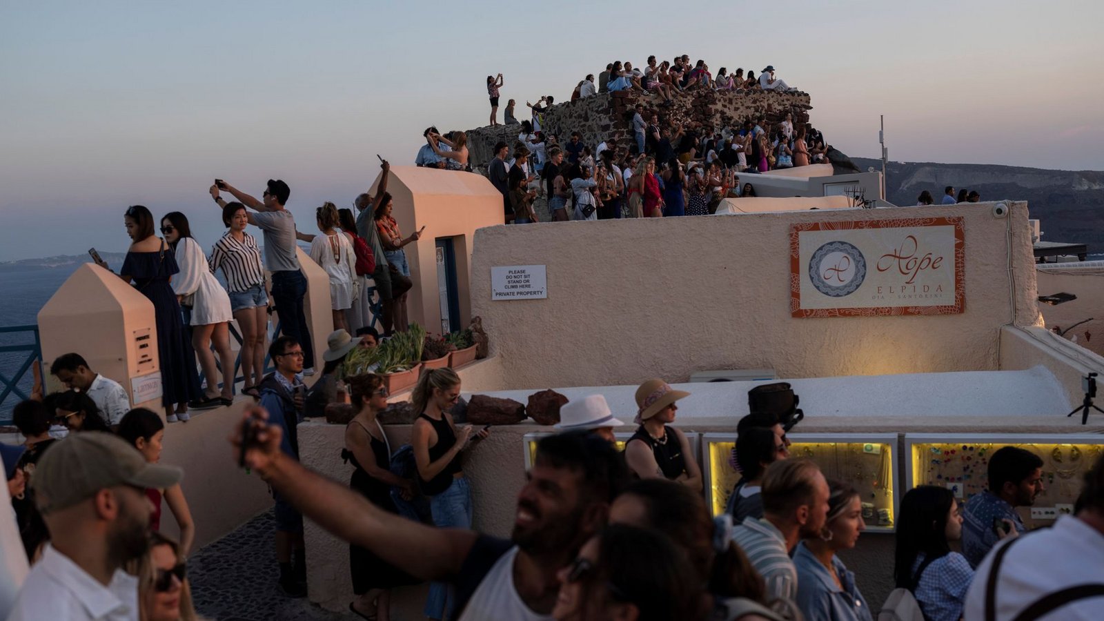Touristen machen Selfies und genießen den Sonnenuntergang in Oia auf der Insel Santorini (Archivfoto).Foto: Petros Giannakouris/AP/dpa/Petros Giannakouris
