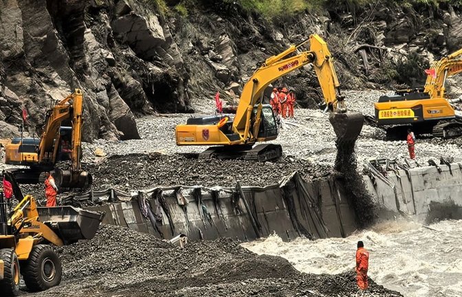 Auf diesem von der Nachrichtenagentur Xinhua veröffentlichten Foto sind Rettungskräfte zu sehen, die mit schwerem Gerät eine Straße freiräumen, die zu den von Schlammlawinen betroffenen Gebieten in Xigaze in der Autonomen Region Tibet im Südwesten Chinas führt.<span class='image-autor'>Uncredited/Xinhua/AP/dpa</span>