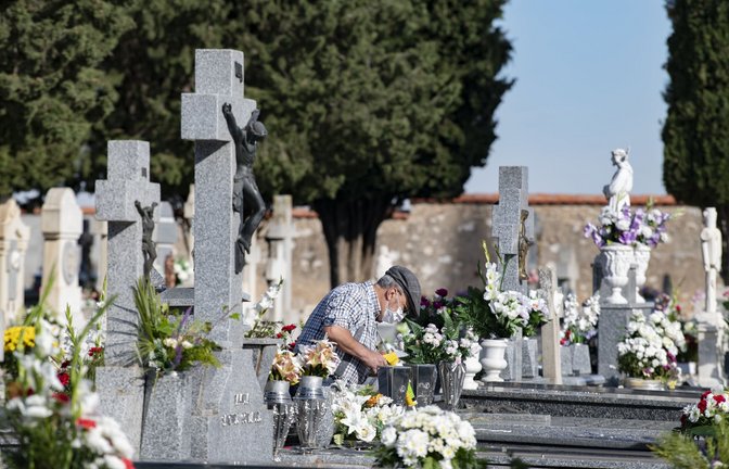 In Spanien legt ein älterer Mann an Allerheiligen Blumen auf ein Grab.<span class='image-autor'>Foto: dpa/Europa Press</span>