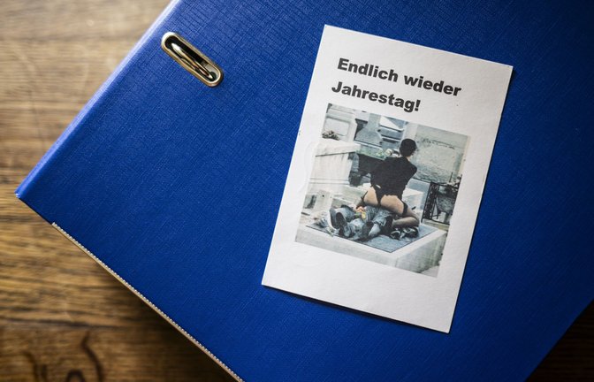 Geschmacklose Post: Zum Todestag von Susannes Ex-Mann wird dem Paar eine Karte zugeschickt, darauf zu sehen eine Frau in Unterwäsche auf einem Grab. Der Ordner mit dem belastenden Material ist prall gefüllt.<span class='image-autor'>Foto: Andreas Reiner</span>