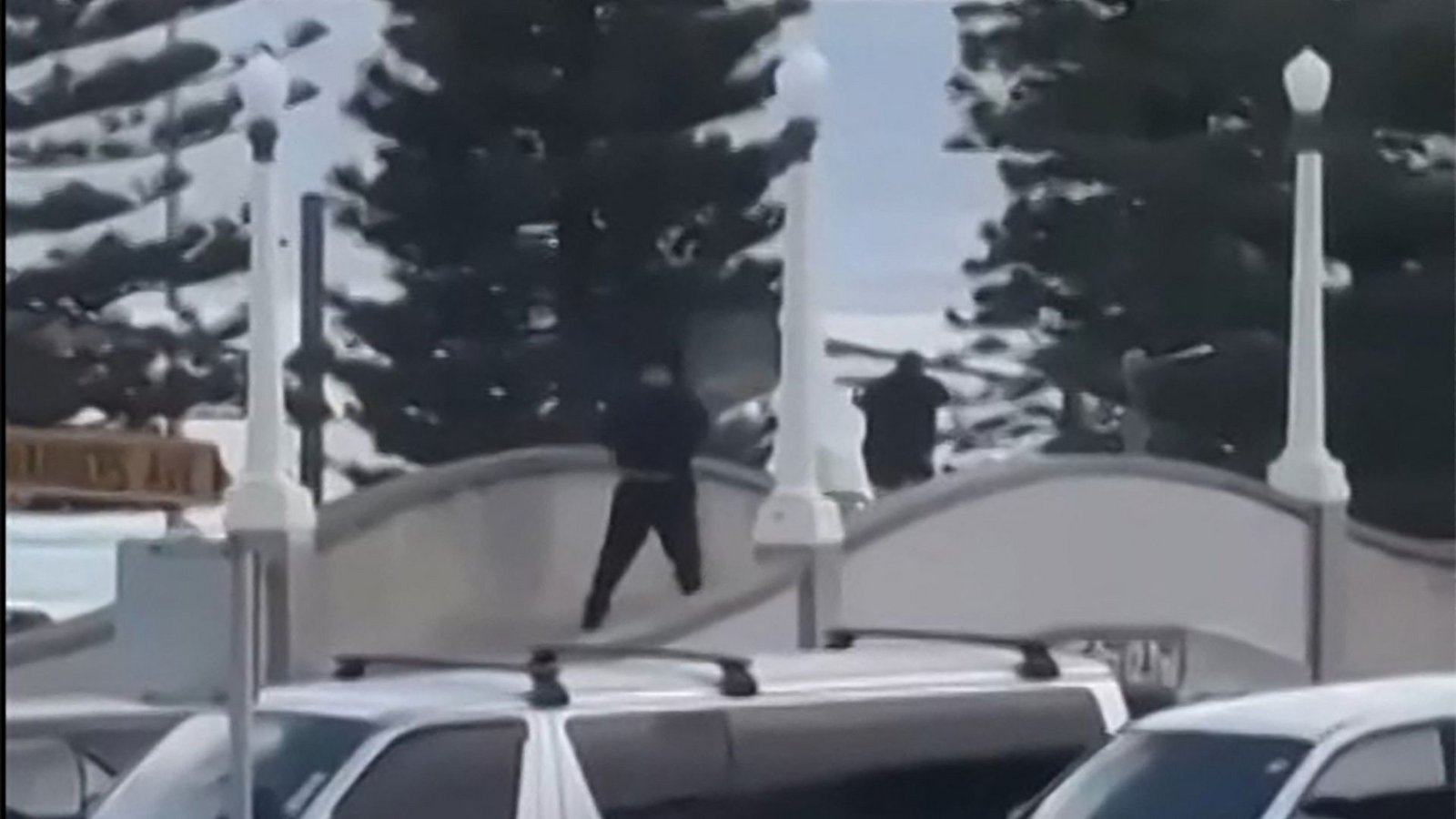 Dieser aus einem von Timothy Brant-Coles zur Verfügung gestellten UGC-Video stammende Bildschirmmitschnitt zeigt zwei schwarz gekleidete bewaffnete Täter, die am 14. Dezember 2025 auf einer Brücke am Bondi Beach in Sydney mehrere Schüsse abfeuern.Foto: AFP