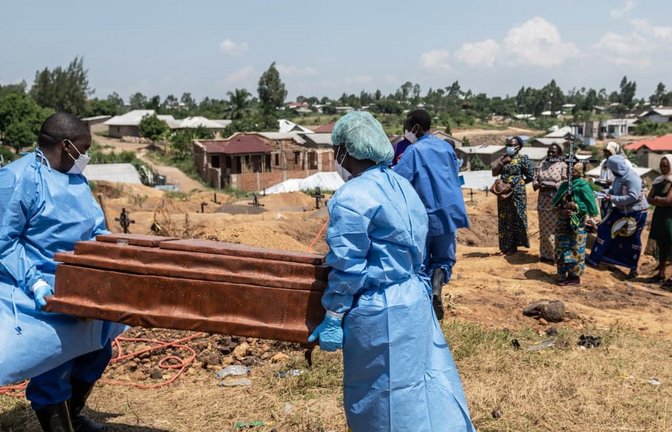 Mitarbeiter des Roten Kreuzes bereiten sich darauf vor ein sechs Monate altes, durch Ebola verstorbenes Waisenmädchen, auf dem Bigo-Friedhof beizusetzen.<span class='image-autor'>Moses Sawasawa/AP/dpa</span>