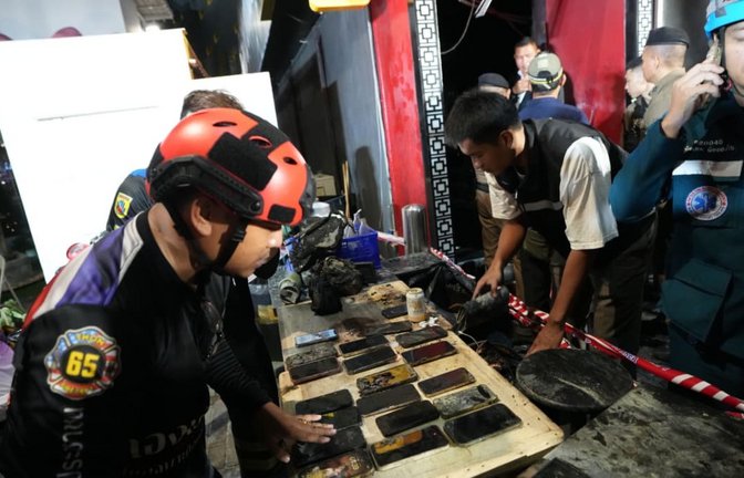 Rettungskräfte bergen die Mobiltelefone von den Opfern eines Brandes. Bei einem Feuer in einem Bierlokal in der thailändischen Hauptstadt Bangkok sind nach Medienberichten mehrere Menschen ums Leben gekommen.<span class='image-autor'>Sakchai Lalit/AP/dpa</span>