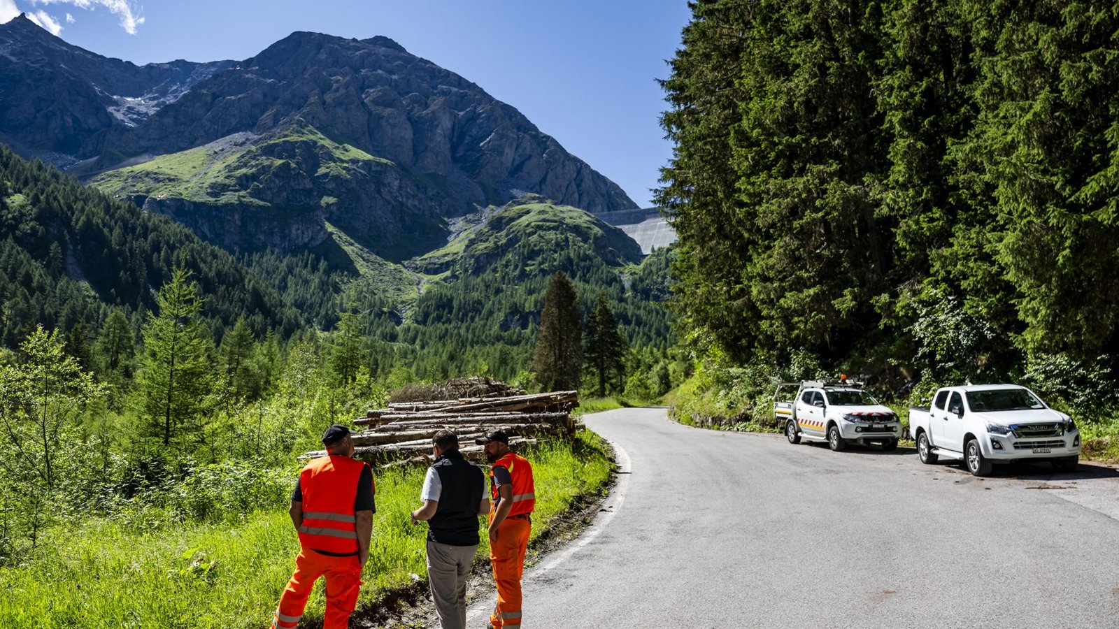 Gregory Logean, Präsident der Gemeinde Heremence, spricht mit Männern auf der gesperrten Straße vor der Staumauer Grande Dixence im Wallis.Foto: Jean-Christophe Bott/KEYSTONE/dpa