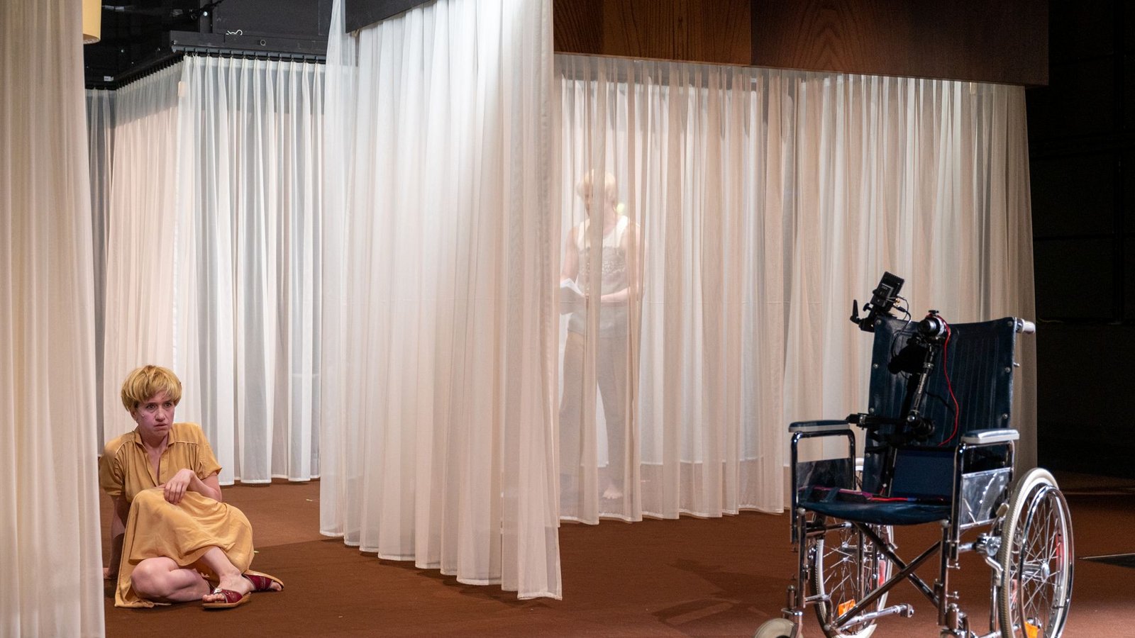 Ein Rollstuhl mit Kamerastativ und Tablet ist das Vehikel für Renates virtuelle Reanimation ihres Sohnes. Das Stück von Clemens J. Setz ist eines der sieben eingeladenen Stücke zu den renommierten Mülheimer Theatertagen 2023.Foto: Schauspiel Stuttgart/Björn Klein
