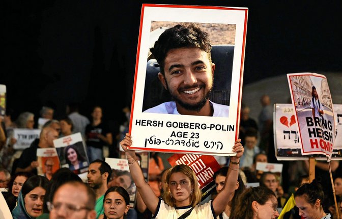 Eine junge Frau hält ein Bild von Hersh Goldberg-Polin nach oben. Jetzt wurde der 23-Jährige ermordet.<span class='image-autor'>Foto: AFP/AHMAD GHARABLI</span>
