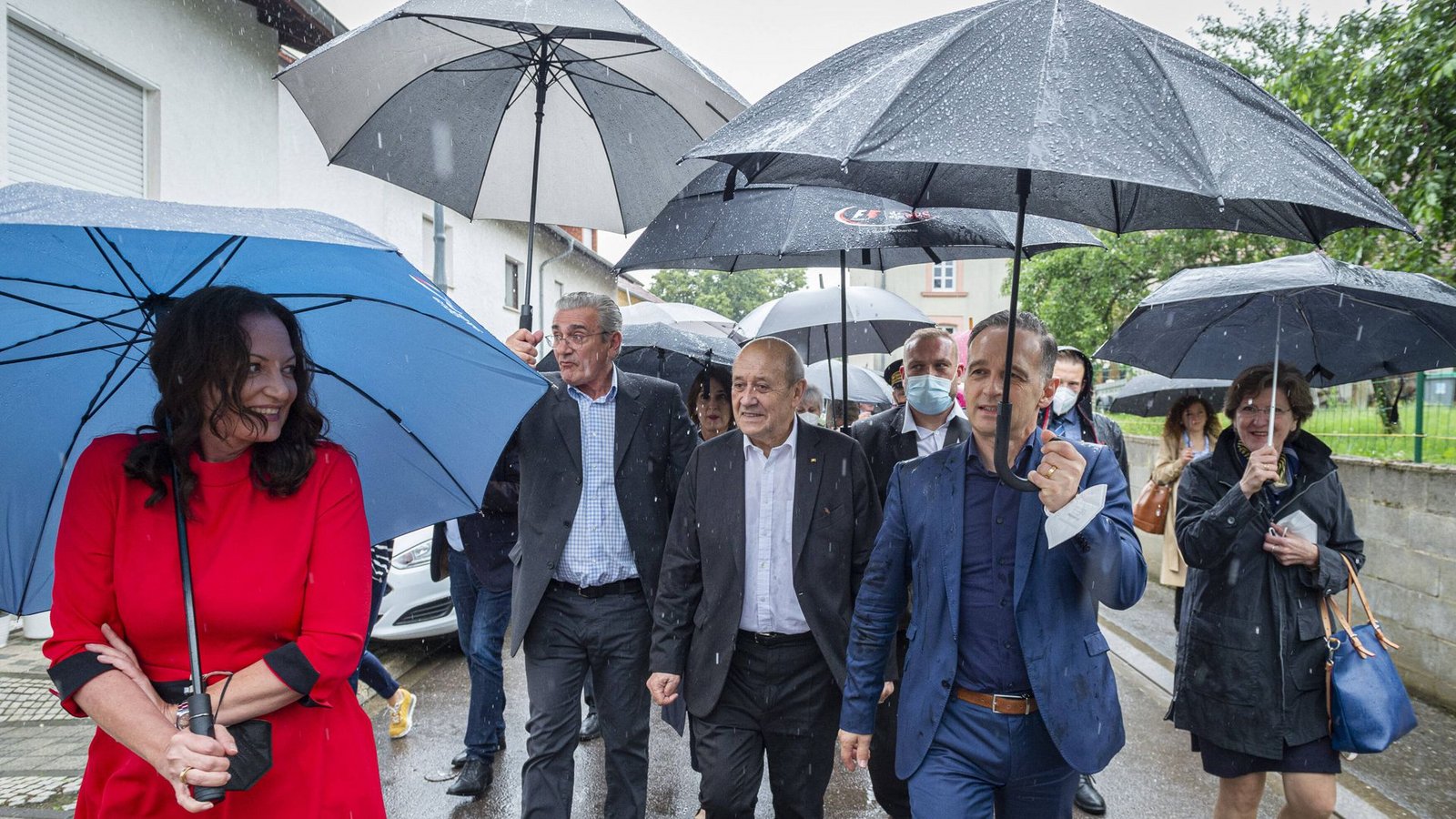Juli 2021: Außenminister Heiko Maas trifft sich mit dem französischen Außenminister Jean-Yves Le Drian im deutsch-französischen Grenzort Leidingen im Saarland. Trotz Dauerregens ist die Laune der Minister bestens. Ob das auch an Natalia Wörner liegt, die in ihrem knallroten Kleid die Blicke auf sich zieht?Foto: imago images/BeckerBredel/BeckerBredel via www.imago-images.de
