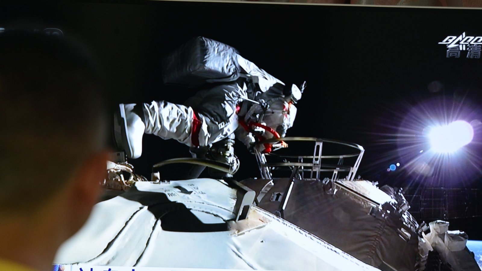 Ein Mann verfolgt vor dem Fernseher die Live-Übertragung eines Außeneinsatzes an der Raumstation "Tiangong" (Archivbild).Foto: Sheldon cooper/SOPA Images via ZUMA Wire/dpa