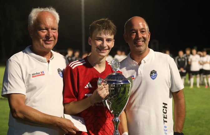 Heimerdingens Matchwinner Paul Jauß (Mi.) strahlt mit dem Pokal um die Wette, den er von Bernd Feyler (Abteilungsleiter Fußball TSV Flacht, li.) und Nico Lautenschlager (Vorsitzender TSV Flacht, re.) entgegennimmt.<span class='image-autor'>Andreas Gorr</span>