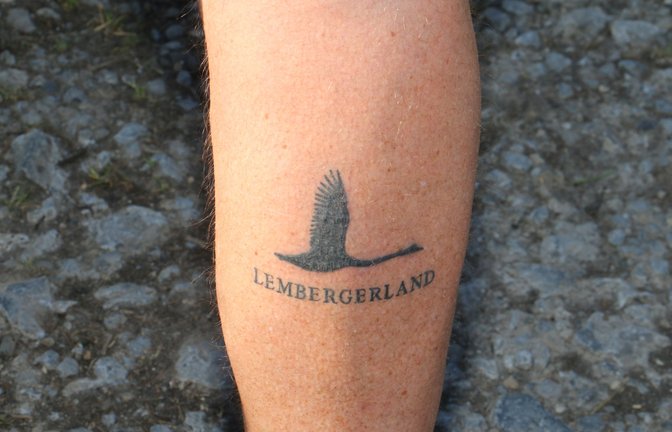 Bei Horst Mäule aus Roßwag geht die Liebe zum Lembergerland unter die Haut, das zeigt die Tätowierung an der Wade. Der Rubbeltest am Rande des 401-Stäffele-Teamlaufs überzeugte davon, dass das Tattoo echt ist. Groß muss auch die Liebe zum Wein bei den Gewinnerteams sein, denn dort werden die schwersten Teilnehmer mit Wein aufgewogen. Bertram Haak, Markenbeauftragter der Lembergerland Kellerei, meldet die Flaschenanzahl: Siegerteam Frauen: 88 Flaschen Wein, sie durften zu zweit auf die Waage. Siegerteam Männer: 88 Flaschen, Siegerteam Mixed 83. Na dann: Prost. <span class='image-autor'>Foto: Rücker</span>