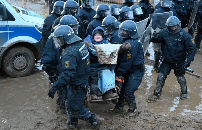 Baden-württembergische Polizisten tragen beim Einsatz in Lützerath am vergangenen Wochenende einen demonstrierenden  Rollstuhlfahrer weg.<span class='image-autor'>Foto: dpa/Henning Kaiser</span>