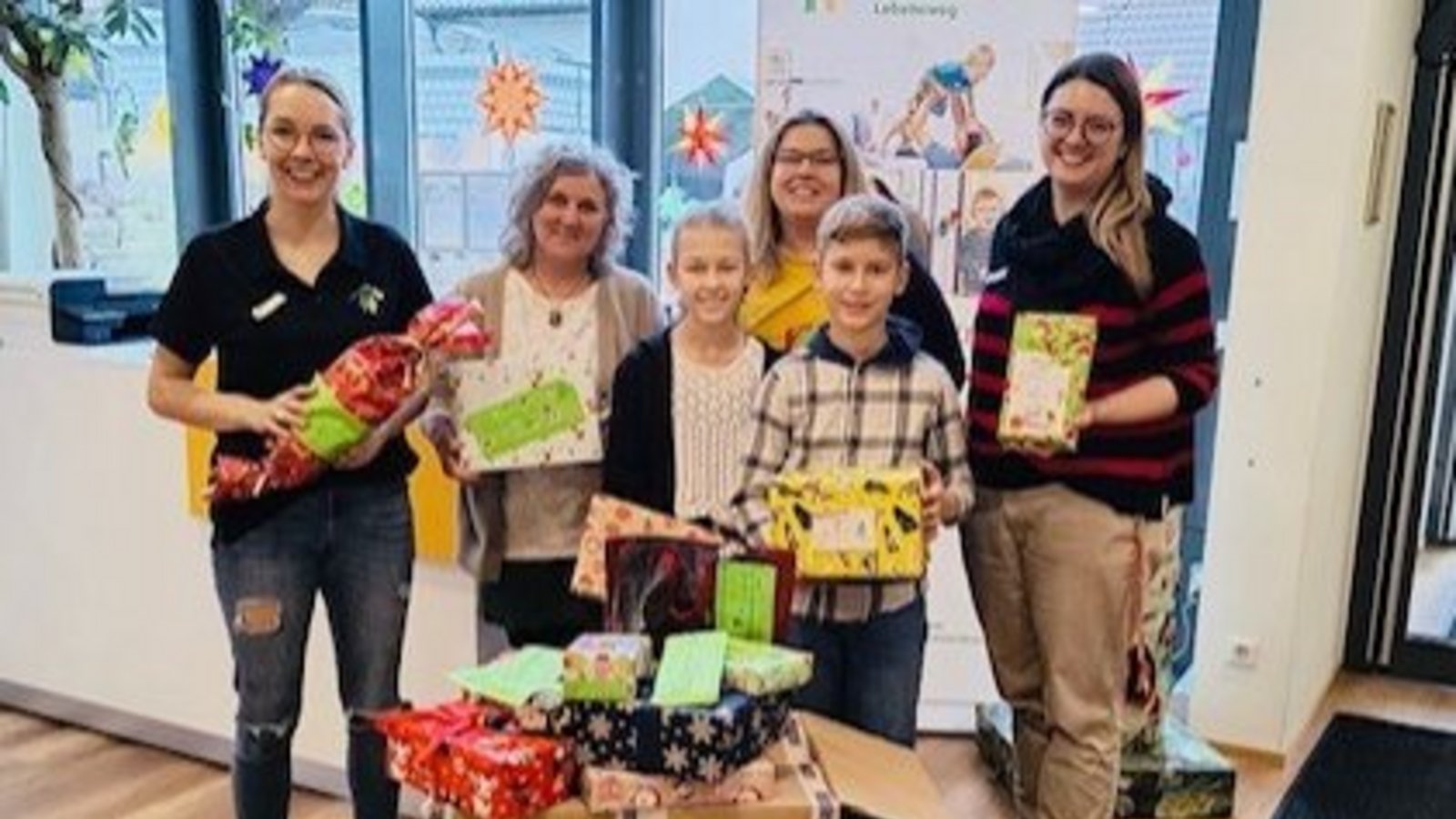Mitorganisatorin Christiane Lorenz (Hinten in der Mitte) überreicht gemeinsam mit Nora und Josha vom Lichtenstern-Gymnasium die Geschenke in der Familienherberge Lebensweg in Schützingen. Foto: p Mitorganisatorin Christiane Lorenz (Hinten in der Mitte) überreicht gemeinsam mit Nora und Josha vom Lichtenstern-Gymnasium die Geschenke in der Familienherberge Lebensweg in Schützingen. Foto: p