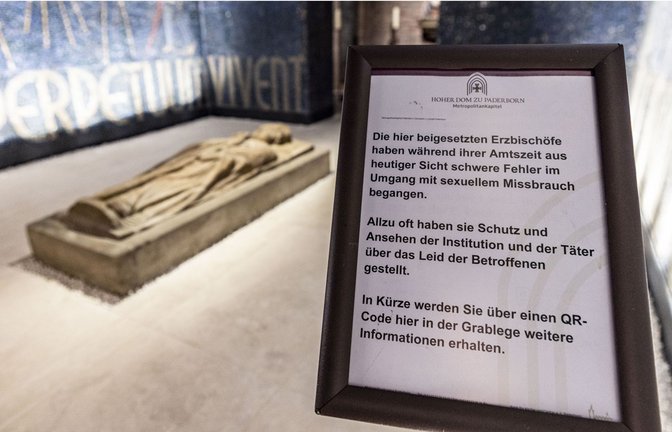 In der Grabkammer der Krypta des Doms steht ein Hinweisschild zu den Fehlern der dort beigesetzten Erzbischöfe des Erzbstums Paderborn im Umgang mit sexuellem Missbrauch in der katholischen Kirche.<span class='image-autor'>Foto: picture alliance/dpa/Christoph Reichwein</span>