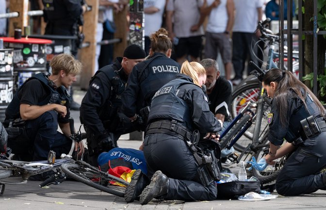 Polizisten knien in der Nähe des Frankfurter Hauptbahnhofs am Boden und kümmern sich um einen Verletzten.<span class='image-autor'>Foto: Boris Roessler/dpa</span>