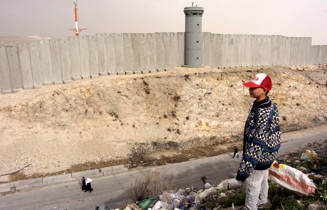 Palästinensischer Junge schaut auf eine Grenzmauer. Israels Regierung will Land im Westjordanland als „Staatseigentum“ registrieren (Archivfoto).<span class='image-autor'>Foto: &nbsp;</span>