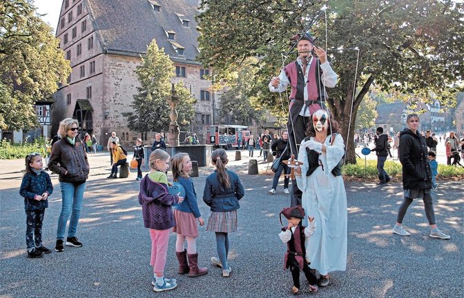Ein Stelzenmann und eine Puppenspielerin bummeln zur Freude der Besucher über den Klosterplatz.  Foto: Filitz
