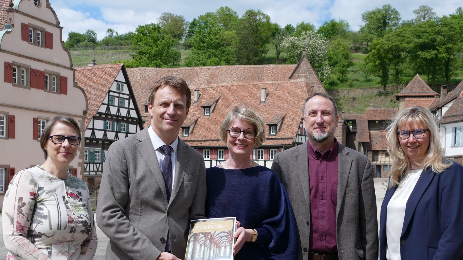 Präsentieren im Klosterhof stolz den Tagungsband über das Kloster Maulbronn (von links): Sandra Eberle (Konservatorin Staatliche Schlösser und Gärten), Kai Fischer (Abteilungsleiter Finanzministerium), Patricia Alberth (Geschäftsführerin Staatliche Schlösser und Gärten), Michael Kohler (Programmleiter Verlag Regionalkultur) und Alexandra Müller (Leiterin Kloster Maulbronn).  Foto: Weimper