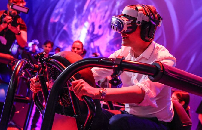 Ein wilder Ritt bei der Gamescom 2024: Hendrik Wüst auf einem "Drachen", genauer gesagt mit virtueller Brille auf einem schwankenden Gestell.<span class='image-autor'>Foto: Oliver Berg/dpa</span>
