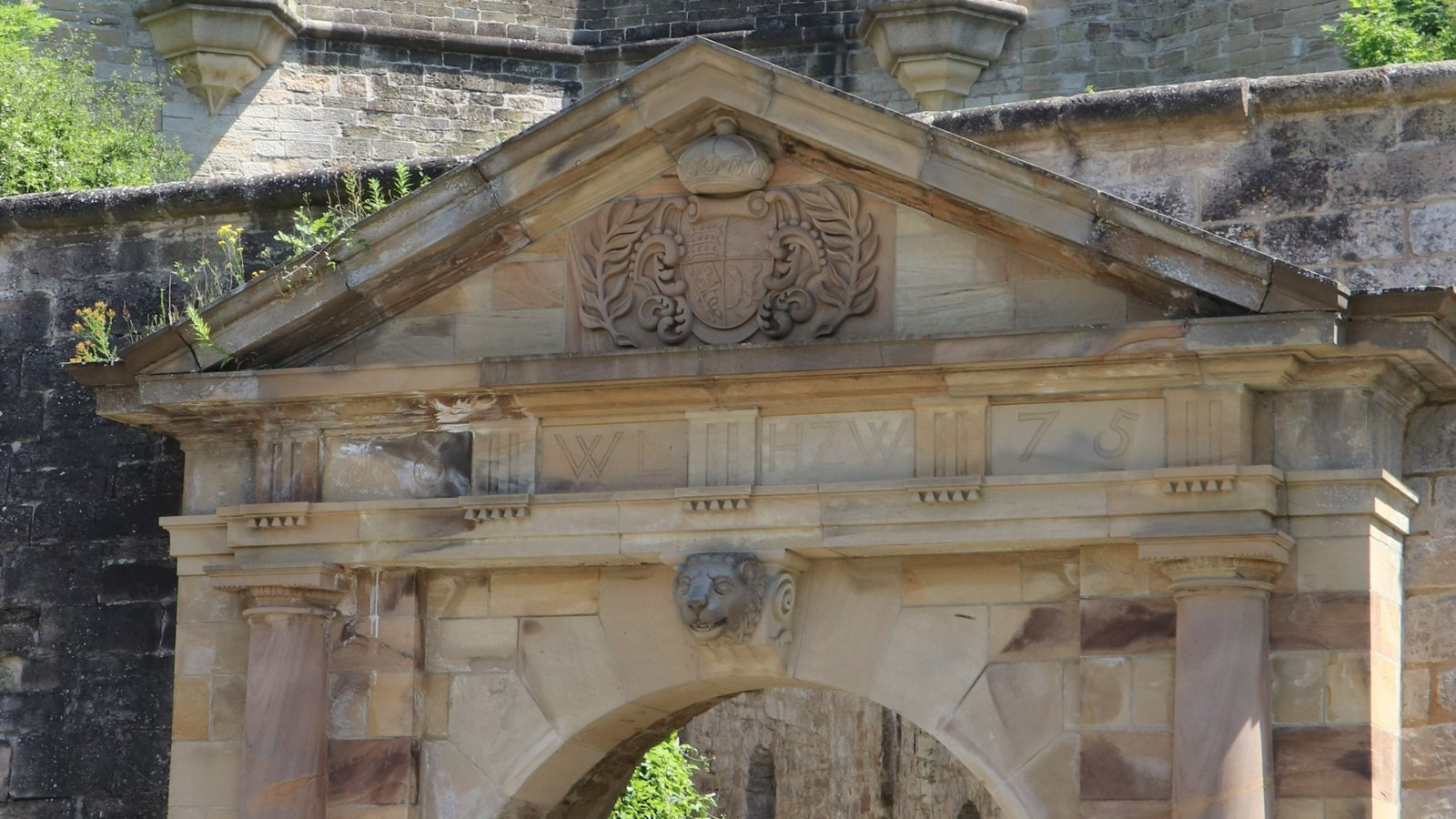 Über dem Eingangsportal erkennt man Inschrift und Jahreszahl sowie das herzogliche Wappen.