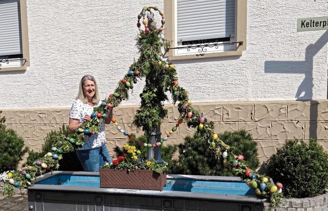 Anwohnerin Suse Herrmann aus Hohenhaslach hat den Dorfbrunnen an der Steige mit grünen Girlanden aus Efeu- und Thujazweigen und kunterbunten Ostereiern geschmückt. Foto: Glemser