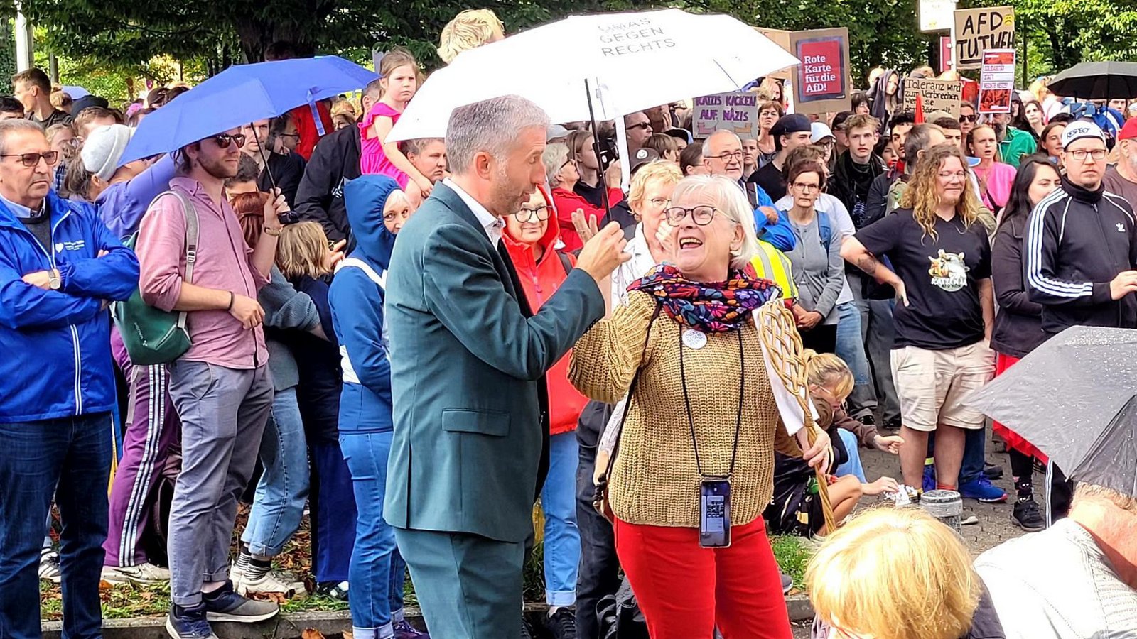 Es regnet kurzzeitig. Eine Frau reicht Palmer einen Schirm.Foto: StZN/Michael Bosch