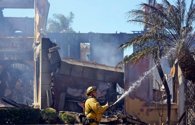 Feuerwehrmann Mike Mejia bei Löscharbeiten im kalifornischen Laguna Niguel. Ein von starkem Pazifik-Wind angefachtes Buschfeuer hat dort mehrere Häuser zerstört, darunter wohl auch Villen im Millionenwert.<span class='image-autor'>Foto: Marcio Jose Sanchez/AP/dpa</span>