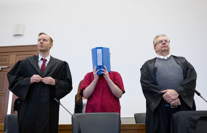Der Angeklagte im Prozess um den Mord an der 14-jährigen Ayleen verbirgt sein Gesicht hinter einem Aktenordner.<span class='image-autor'>Foto: dpa/Boris Roessler</span>