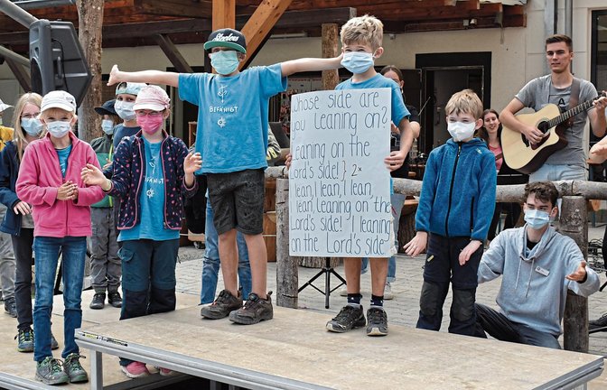 Musik sorgt für gute Stimmung unter den jungen Teilnehmern des Waldheims in Sersheim. Ein Junge zeigt ein Plakat mit den Lyrics eines englischen christlichen Lieds, damit alle mitsingen können.  Fotos: Mattausch
