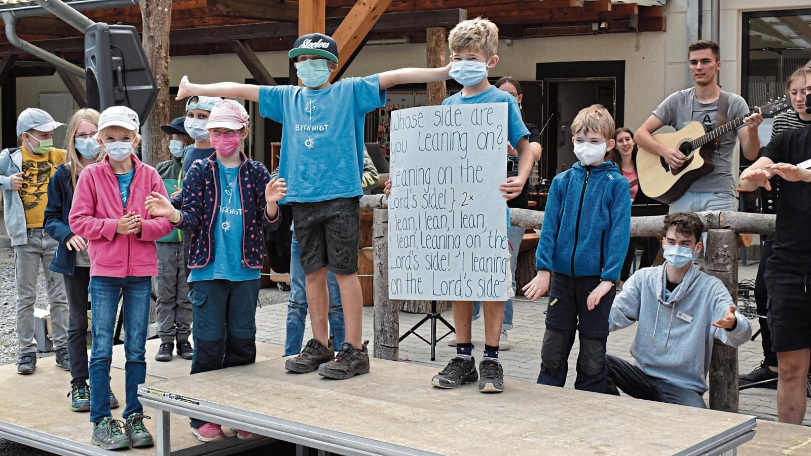 Musik sorgt für gute Stimmung unter den jungen Teilnehmern des Waldheims in Sersheim. Ein Junge zeigt ein Plakat mit den Lyrics eines englischen christlichen Lieds, damit alle mitsingen können. Fotos: Mattausch Musik sorgt für gute Stimmung unter den jungen Teilnehmern des Waldheims in Sersheim. Ein Junge zeigt ein Plakat mit den Lyrics eines englischen christlichen Lieds, damit alle mitsingen können. Fotos: Mattausch