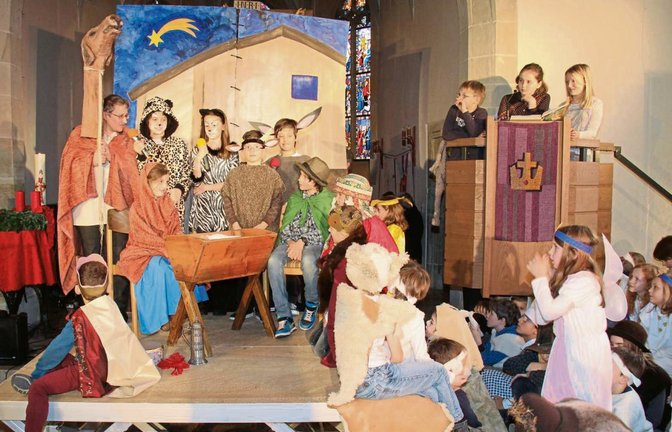Am Ende des Weihnachtssingspiels in der Illinger Cyriakuskirche freuen sich die Teilnehmer über das Kind in der Krippe.  Foto: Elsässer