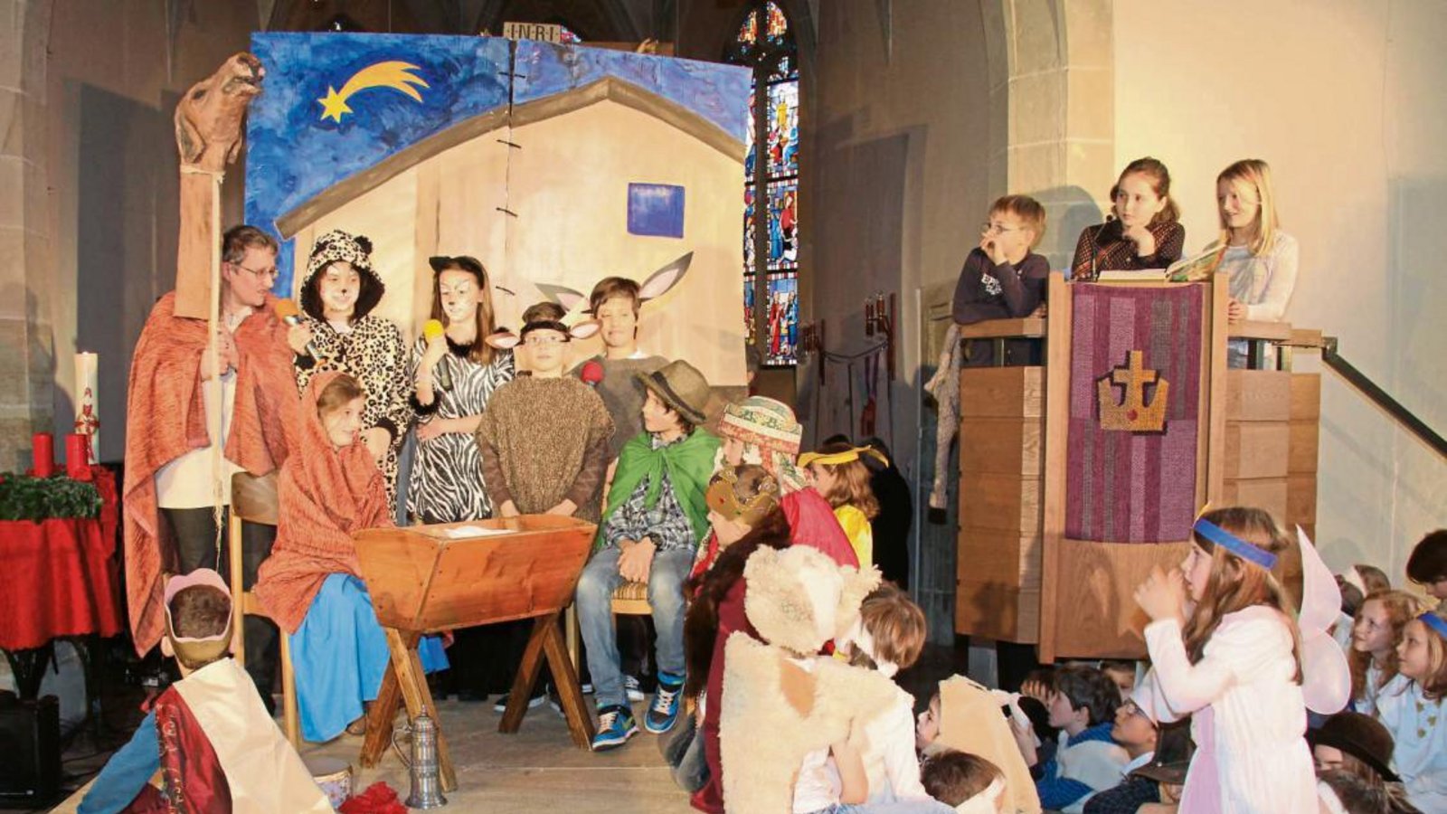 Am Ende des Weihnachtssingspiels in der Illinger Cyriakuskirche freuen sich die Teilnehmer über das Kind in der Krippe.  Foto: Elsässer