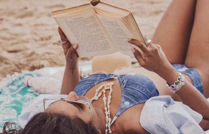 Wo liest es sich schon besser als am Strand? (Symbolbild)<span class='image-autor'>Foto: IMAGO/Wirestock</span>