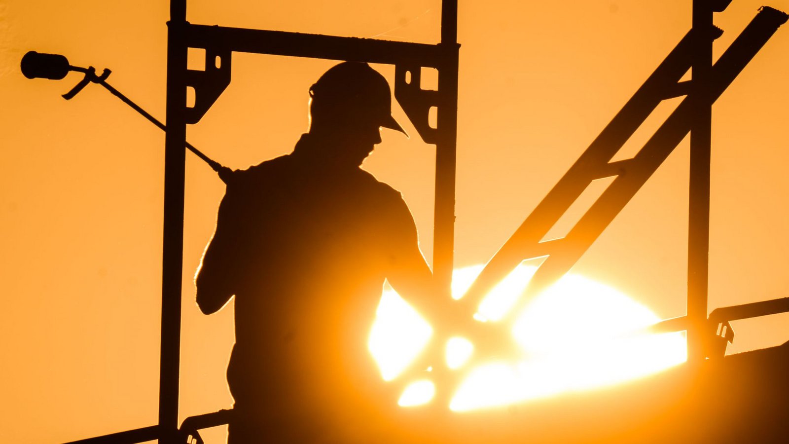Ein Bauarbeiter steht mit einem Gasbrenner beim Bau eines Mehrfamilienhauses, als am Horizont die Sonne aufgeht.Foto: dpa/Julian Stratenschulte Ein Bauarbeiter steht mit einem Gasbrenner beim Bau eines Mehrfamilienhauses, als am Horizont die Sonne aufgeht.Foto: dpa/Julian Stratenschulte